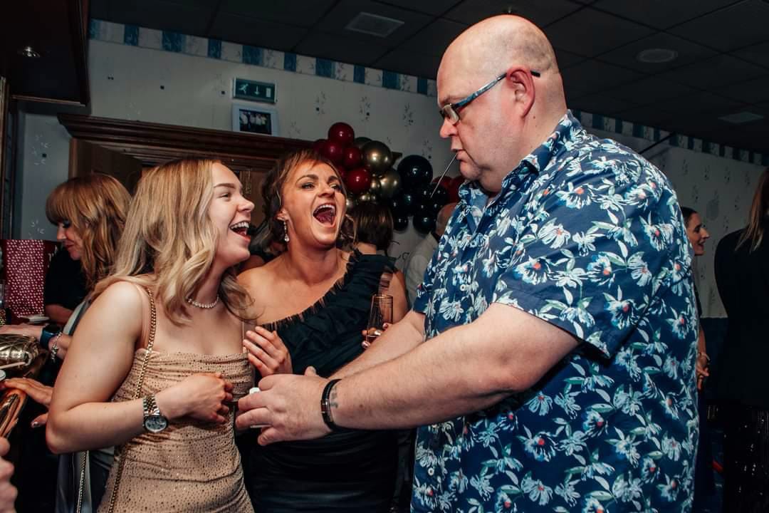 Jason performing close-up magic for two guests at a party, both of them laughing